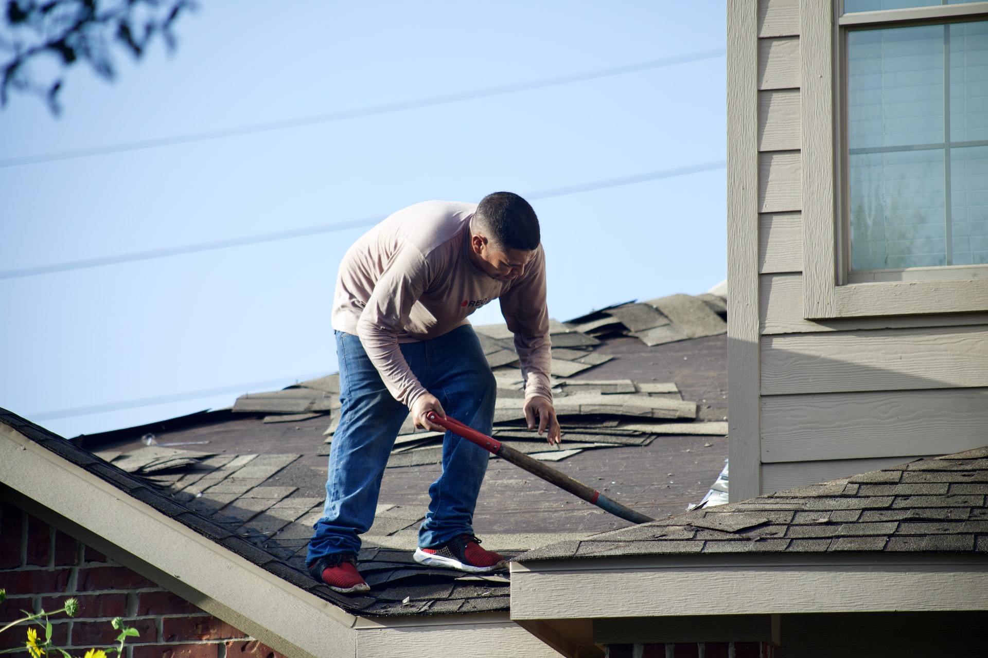 A man on the roof trying to fix one of the common roofing problems new homeowners face.